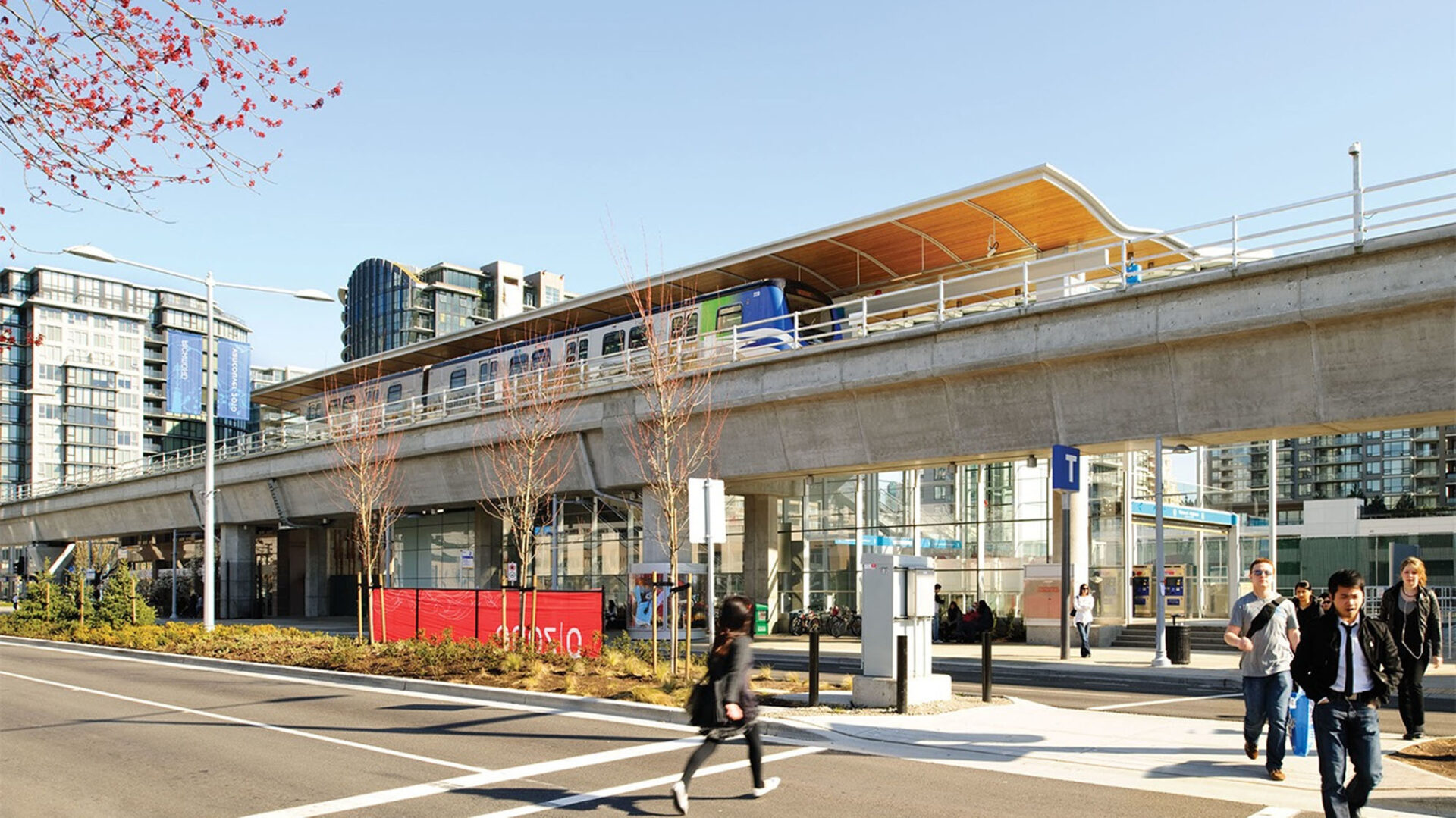 Ground view of a skytrain station with numerous people walking by